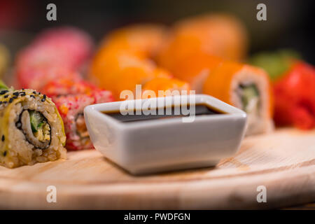 Bol de sauce de soja sur une carte de sushi avec du poisson cru et des algues fraîches rouleaux dans un close up low angle view Banque D'Images