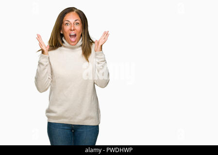 Beau moyen age adult woman wearing winter sweater sur fond isolé célébrant la folie et surpris du succès avec bras levés et ouvert ey Banque D'Images