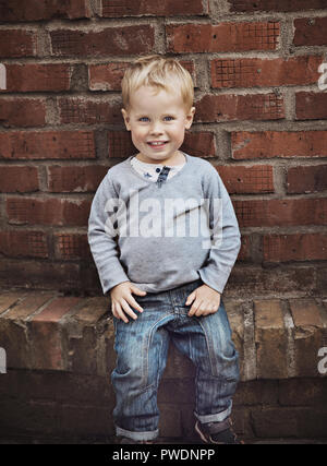 Adorable petit enfant posant sur vieux mur rouillé, Banque D'Images