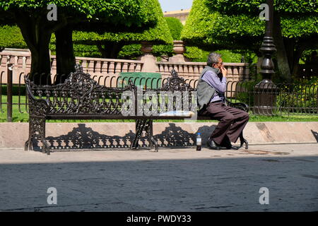 Mexicain d'âge moyen assis sur un banc de parc sur la place principale de Leon, Guanajuato, Mexique; homme âgé, dans ses 50s ou 60s ans. Banque D'Images