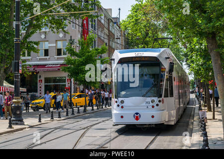 Un Kabatas-Bagcilar T1 tramway Métro électrique descend dans un boulevard passé les bâtiments et les personnes dans le district de Fatih de la Corne d'or, Istanbul, Turke Banque D'Images