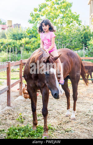 Enfant, kid enfants à cheval, cheval girl joie heureux concept, farm animal animaux étalon brun, concept rural, Agriculture Canada, Italie Banque D'Images