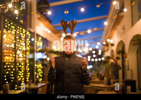 Les gens, les vacances de Noël - concept et surpris l'homme dans les cornes de cerf tenant deux baguettes à la lumière ou à l'extérieur des bengals Banque D'Images