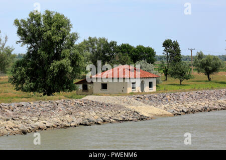 Cottage dans la direction de Vulturu à Sulina du Danube, rive du Danube, promenade au bord de la rivière, paysage, groupe d'arbres, de rochers, digue du Danube la protection contre les inondations, marais, terres agricoles, Roumanie, comté de Tulcea, Dobroudja, Réserve de biosphère du delta du Danube, Delta du Danube, delta de rivière, estuaire, embouchure de la rivière du Danube à la mer Noire, l'UNESCO World Heritage Site, repère naturel Banque D'Images