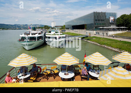 L'Autriche, Haute Autriche, Linz sur le Danube, capitale de la province de Haute-Autriche, capitale européenne 2009, Danube river cruise, parasols, les touristes sur la plage arrière de la voiture de patrouille aROSA Mia, les navires d'excursion à l'embarcadère Donaulaende droit, le Lentos Art Museum, dans l'arrière-plan l'hôtel Arcotel Linz Banque D'Images