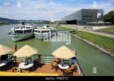 L'Autriche, Haute Autriche, Linz sur le Danube, capitale de la province de Haute-Autriche, capitale européenne 2009, Danube river cruise, parasols, les touristes sur la plage arrière de la voiture de patrouille aROSA Mia, les navires d'excursion à l'embarcadère Donaulaende droit, le Lentos Art Museum, dans l'arrière-plan l'hôtel Arcotel Linz Banque D'Images