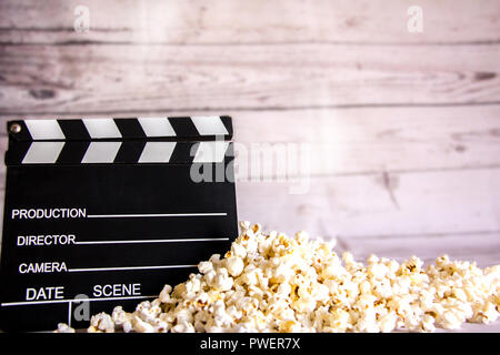 Popcorn et clap sur fond de bois blanc pour le cinéma historique Banque D'Images