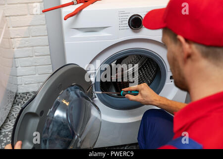 Avec un tournevis pour réparation réparateur porte lave-linge Banque D'Images