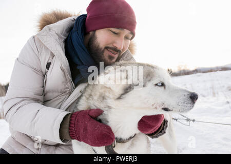 Portrait de l'homme asiatique barbu hugging superbe chien husky appréciant belle journée d'hiver sur promenade dans les bois, copy space Banque D'Images