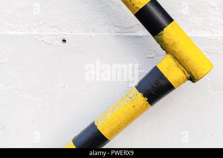 Garde-corps en métal noir jaune avec précaution sur mur blanc, fond résumé objet industriel Banque D'Images