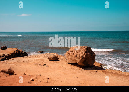 Plage avec gros rocher, bleu océan sous un ciel bleu. Banque D'Images