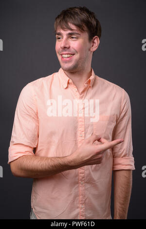 Portrait of young handsome businessman contre l'arrière-plan gris Banque D'Images