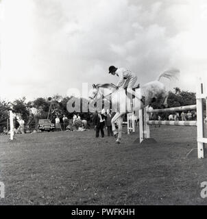 1967, historiques, une adolescente sautant une clôture ou d'un obstacle à un événement équestre de l'extérieur, Aylesbury, Buckinghamshire, Angleterre, Royaume-Uni. Banque D'Images