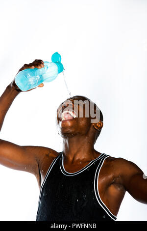 Jeune homme sportif africain rire verser de l'eau d'une bouteille d'eau sur son front Banque D'Images