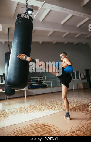 Male boxer hitting punching bag à la salle de sport. Entraînement de boxe, Banque D'Images