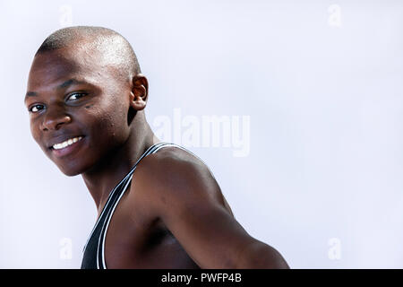 Beau jeune homme africain portant un t-shirt de muscle en souriant. Banque D'Images