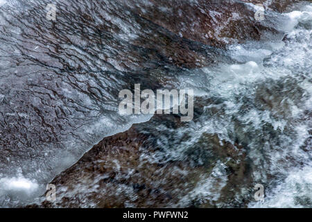 La présentation détaillée de l'eau coule sous la glace dans une rivière. La neige fond des montagnes et s'écoule en ruisseau, Close up. Banque D'Images