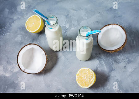 Lait de coco cocktail vegan en bouteille sur fond de béton. Banque D'Images