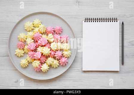 Mini meringues sur la plaque grise et blank notepad over white background, vue de dessus. Mise à plat, d'en haut, vue d'en haut. Banque D'Images