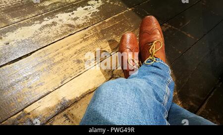 Chaussures en cuir brun, jeans, isolé sur fond de bois Banque D'Images