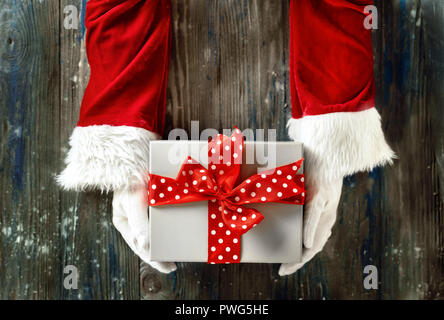 Vue de dessus de Santa's hands holding cadeau de Noël sur fond de bois Banque D'Images