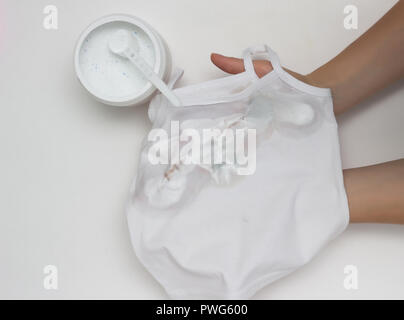 Girl met sur un T-shirt blanc sale avec des taches, enlève les taches, les mains, close-up, fond blanc, l'eau de javel Banque D'Images