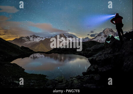 Randonneur sur haut de rochers en admirant les étoiles reflète dans Lacs De Cheserys avec le massif du Mont Blanc en arrière-plan, Chamonix, Haute Savoie, France Banque D'Images