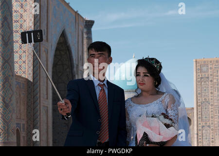 Un groom ouzbek et de l'épouse de prendre au cours de la conférence préparatoire selfies session photographie de mariage dans le Reghistan place publique qui était le cœur de la ville antique de Samarkand alternativement Samarqand de la dynastie timouride en Ouzbékistan Banque D'Images