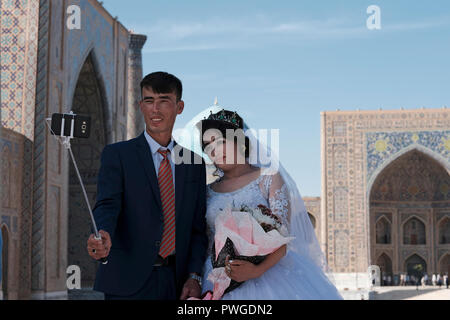 Un groom ouzbek et de l'épouse de prendre au cours de la conférence préparatoire selfies session photographie de mariage dans le Reghistan place publique qui était le cœur de la ville antique de Samarkand alternativement Samarqand de la dynastie timouride en Ouzbékistan Banque D'Images