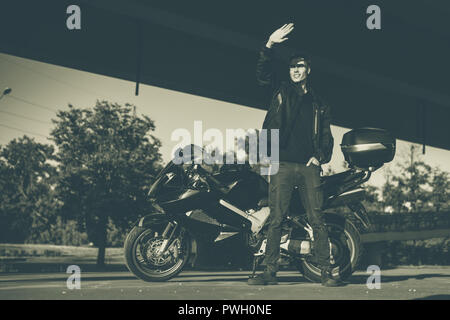 Un jeune blanc est debout à côté d'une moto. Banque D'Images