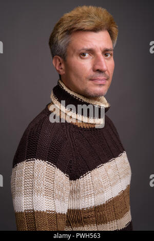 L'homme aux cheveux blonds portant Pull col roulé contre le dos gris Banque D'Images