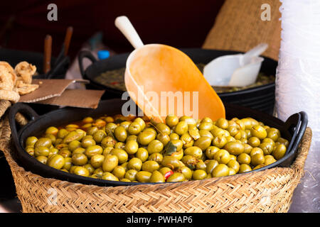 Green olives espagnoles dans un panier au marché de rue avec une grande cuillère Banque D'Images