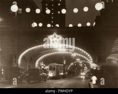 Noël dans les années 1930. L'animation de la rue Kungsgatan est décoré avec des lumières de Noël. Le tramway et les voitures passent sous un des ponts dans la rue. Suède 1930 Banque D'Images