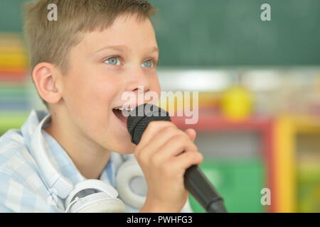 Portrait of a cute boy singing karaoke Banque D'Images