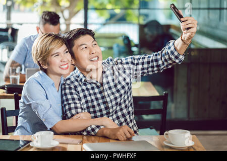 Couple qui dans le café selfies Banque D'Images