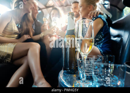 Les femmes et les hommes la fête avec des boissons dans une voiture limousine Banque D'Images