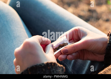 Rouler une cigarette de tabac. Close up image de femmes en plein air dans l'arrière-plan d'ensoleillement Banque D'Images