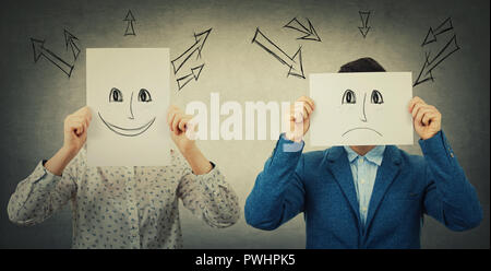 Businessman and businesswoman couvrant leur visage à l'aide de feuilles avec appelée heureux et triste des émoticônes, comme un masque pour cacher son émotion réelle de la société. Banque D'Images