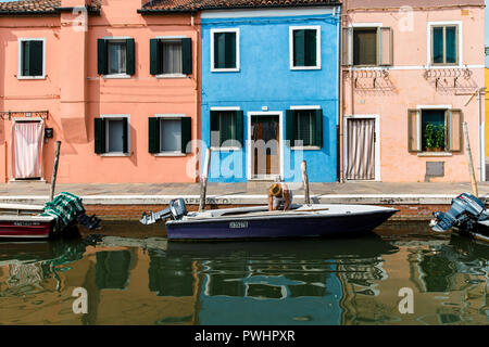 Maisons colorées traditionnelles reflétant dans le canal avec de petits bateaux dans l'île de Burano, Venise, Italie Banque D'Images