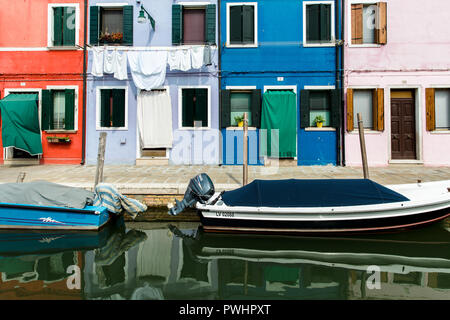 Maisons colorées traditionnelles reflétant dans le canal avec de petits bateaux dans l'île de Burano, Venise, Italie Banque D'Images