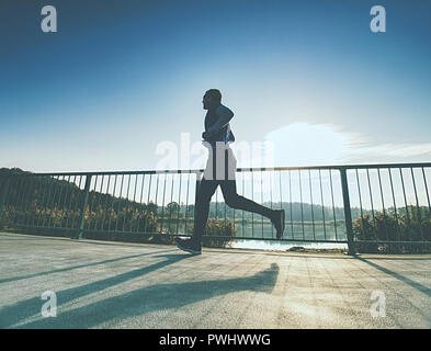 L'homme sportif courir jusqu'au pont . Sport et vie concept - slim homme qui court sur le pont de la ville. Travail à l'extérieur des canaux chauds Banque D'Images