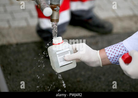 Les détails avec les mains d'un médecin en blouse médicale tenant un destinataire en plastique pour tester si l'eau d'un réservoir est potable Banque D'Images