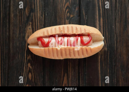 Hot-dog à la tomate sur fond de bois foncé.photo avec co Banque D'Images