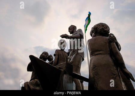 Le drapeau national ouzbek qui oscille sur un monument de l'ère soviétique (créé par le sculpteur Dmitri Ryabichev en 1982) pour le forgeron Shaakhmed Shamakhmudov Akramova Bahri et sa femme qui a adopté 15 enfants de différentes nationalités, qui ont perdu leurs parents et ont été évacués à Tachkent au cours de la DEUXIÈME GUERRE MONDIALE, placé dans le parc de l'amitié à Tachkent, capitale de l'Ouzbékistan. Au cours de la Seconde Guerre mondiale plus d'un million de personnes évacuées, dont plus de 200 000 enfants ayant perdu leurs parents, ont été déplacés à l'Ouzbékistan. Chaque jour, entre 200 et 400 orphelins est arrivé à la gare de Tachkent. Banque D'Images