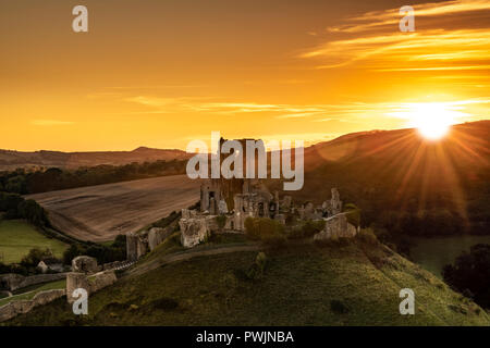 Le soleil se couche derrière les collines de Purbeck dans Dorset comme fondus Corfe Castle dans les derniers rayons de soleil de fin septembre. Banque D'Images