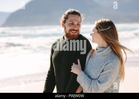 Bel homme à marcher avec sa petite amie sur la plage. Jeune couple ensemble le long du bord de mer. Banque D'Images