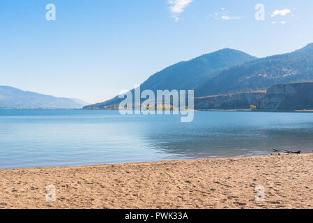 Lac avec plage de sable, montagnes, et ciel bleu Banque D'Images