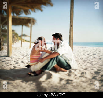 Couple sitting on tropical beach sous palapa Banque D'Images