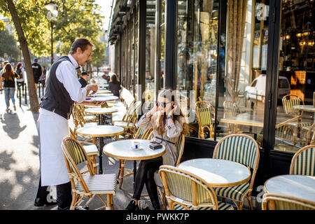 PARIS, FRANCE - 31 août 2018 : du café pour une jeune femme assise à la clientèle française traditionnelle en plein air à Paris Banque D'Images