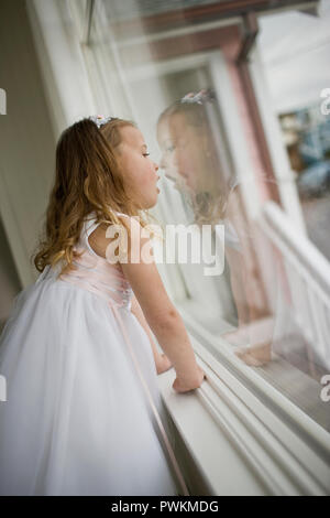 Jeune fille debout à une fenêtre vêtue comme une bouquetière. Banque D'Images